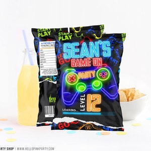 May include: A black chip bag with a neon green and blue video game controller graphic. The bag has the text "Sean's Game On" and "Level 12" in neon colors. The bag is decorated with a black and white pixelated pattern.