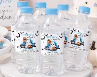 Puede incluir: Botellas de agua de plástico transparente con tapones azul claro y etiquetas personalizadas con un fantasma, calabazas y murciélagos. Las etiquetas dicen "LITTLE BOO is almost due" y "Michael & Sarah's BABY SHOWER" en texto negro y azul con detalles.