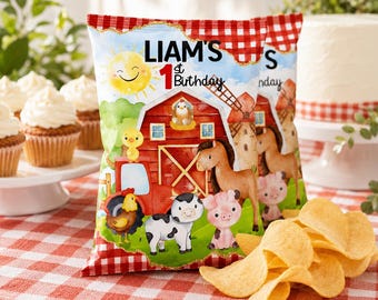May include: A colorful snack bag with a farm theme, featuring a red barn, animals, and the text "LIAM'S 1st Birthday." The bag is filled with potato chips and sits on a red and white checkered tablecloth. Cupcakes and a cake are in the background.