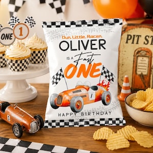 May include: A party scene with a racing theme. A white chip bag with the text "Our Little Racer OLIVER is a Fast ONE" and a race car graphic. Cupcakes, a toy race car, and a bowl of chips are also visible.