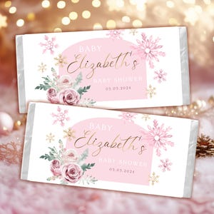 May include: Pink and gold baby shower chocolate bar wrappers with a floral design and snowflakes. The text reads "Baby Elizabeth's Baby Shower 03.05.2024".