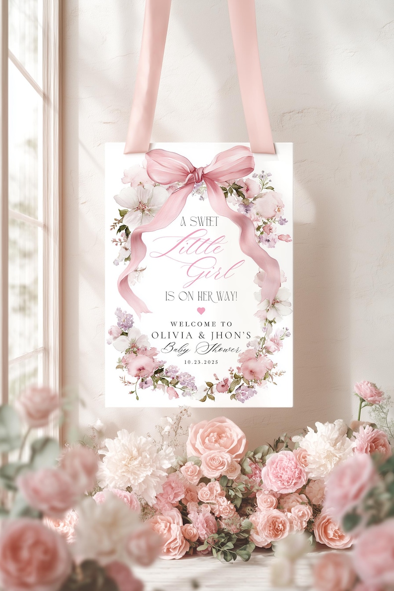 May include: A baby shower sign with a pink ribbon and floral design. The sign reads "A Sweet Little Girl Is On Her Way!" with the names Olivia & Jhon and the date 10.23.2025. The sign is surrounded by pink and white flowers.