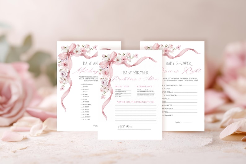 May include: Three baby shower game cards with floral and ribbon details. The cards feature games like "Baby An Matching" and "Price is Right". The design includes pink and white flowers and ribbons, with text in a delicate script font.