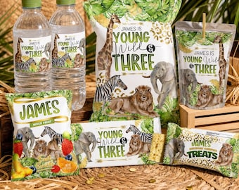 May include: A collection of party supplies with a jungle theme. The items include water bottles, snack bags, and juice pouches, all decorated with illustrations of giraffes, zebras, lions, and elephants. The text "James is Young Wild & Three" is featured on the packaging.