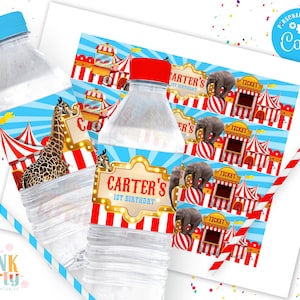 K&ouml;nnte beinhalten: Zwei Wasserflaschen mit blauen Deckeln und Zirkus-Themenetiketten. Die Etiketten zeigen eine Giraffe, Zirkuszelte, Elefanten und den Text "Carter's 1st Birthday". Ein Bogen mit passenden Etiketten und ein gestreifter Strohhalm sind ebenfalls sichtbar.