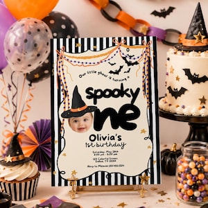 Pode incluir: Uma placa retangular de convite de aniversário com borda listrada em preto e branco, centro creme e o texto "Our little ghoul is turning a spooky one". Inclui a foto de um bebê usando um chapéu de bruxa e detalhes sobre a festa.