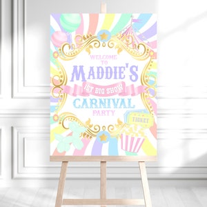 May include: A pastel-colored carnival-themed welcome sign on a wooden easel. The sign features the text "Welcome to Maddie's 1st Big Show Carnival Party" in various fonts and colors, along with carnival graphics like balloons, popcorn, and a ticket.