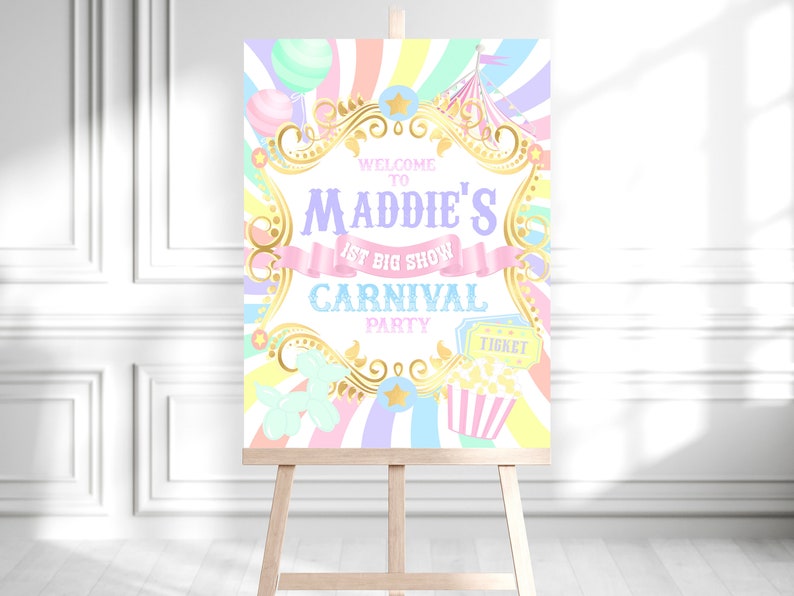 May include: A pastel-colored carnival-themed welcome sign on a wooden easel. The sign features the text "Welcome to Maddie's 1st Big Show Carnival Party" in various fonts and colors, along with carnival graphics like balloons, popcorn, and a ticket.