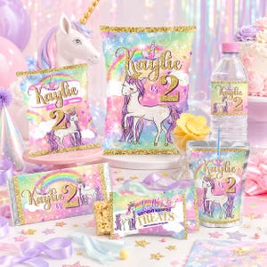 May include: A collection of party supplies with a unicorn theme. The items include chip bags, candy bar wrappers, water bottle labels, a cup, and a Rice Krispies treat wrapper. Each item features a unicorn illustration, the name "Kaylie", and the number "2". The designs have a rainbow and gold glitter accents.