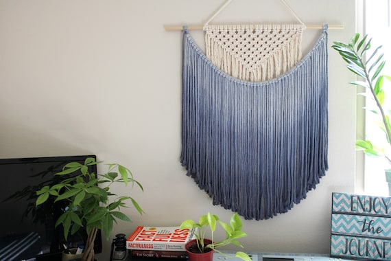 Hand-dip-dyed ombre royal blue macrame tapestry — the labor-intensive dye technique gives it a gradient drama you genuinely can't replicate with a factory print, and 2,315 favorites prove people stop scrolling for it.