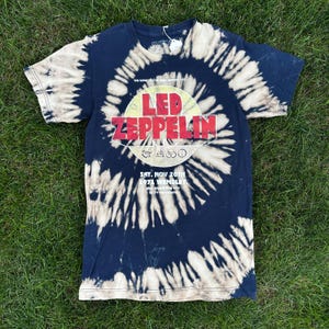 May include: Navy blue tie-dye t-shirt featuring a circular graphic with the band name "LED ZEPPELIN" in red and white. The shirt also includes the text "SAT. NOV 20TH 1971 WEMBLEY". The shirt has a classic crew neck and short sleeves.