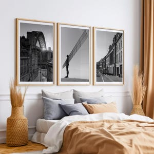 May include: Three black and white photographs of cityscapes in Newcastle upon Tyne, England. The first photo shows the Tyne Bridge, the second photo shows the Angel of the North sculpture, and the third photo shows a street lined with buildings.