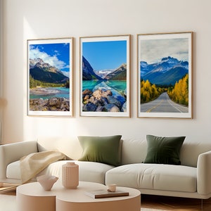 May include: Three framed landscape prints featuring mountain and lake scenes. The prints have gold frames and showcase vibrant colors of blue, green, and yellow. The images depict scenic views of mountains, lakes, and a road.