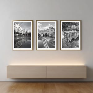 Pode incluir: Um conjunto de três impressões de arte a preto e branco emolduradas com marcos arquitetónicos. A impressão da esquerda mostra um edifício de pedra com arcos, a central mostra uma ponte sobre um rio e a da direita uma ponte de pedra.