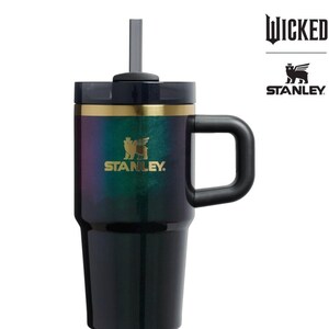Op de afbeelding: Zwarte en iriserende Stanley-beker met een handvat en een rietje. De beker heeft een gouden band en het Stanley-logo. Het woord "WICKED" en het Stanley-logo staan aan de rechterkant van de beker.