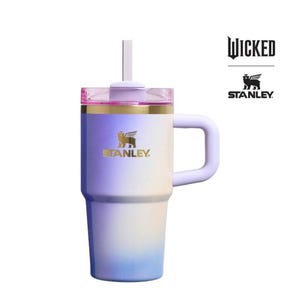 Op de afbeelding: Een Stanley-beker met een kleurovergang in paars, wit en blauw. Hij heeft een handvat, een deksel met een rietje en het Stanley-logo in goud. Het woord "Wicked" staat rechtsboven gedrukt.