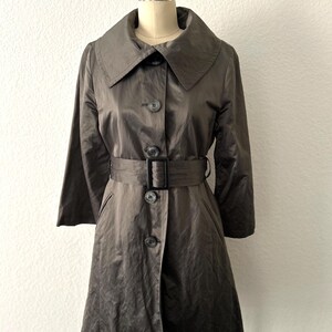 May include: A brown belted trench coat with a large collar and a button closure.