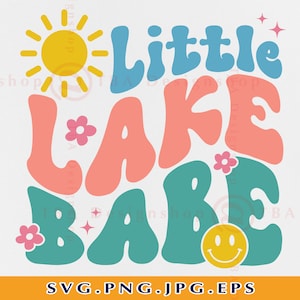 May include: A retro-style graphic design with the text "Little Lake Babe" in colorful, bubbly letters. A yellow sun with rays and pink flowers are included in the design.