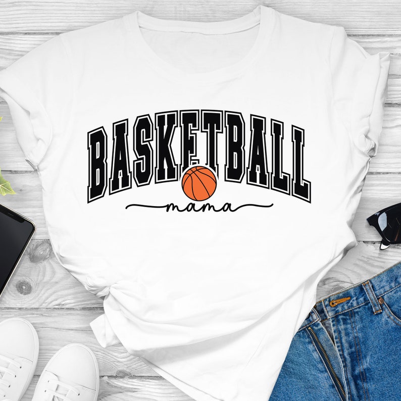 May include: White t-shirt with black text that reads "Basketball mama" with a basketball graphic.