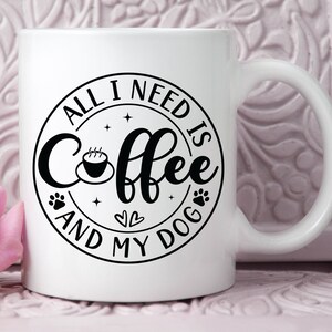 May include: White ceramic coffee mug with a black circle design that says "All I need is coffee and my dog" with a paw print, a heart, and a coffee cup graphic.