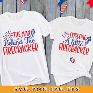 May include: Two white t-shirts with red, white, and blue text and graphics. The larger shirt says "The Man Behind The Firecracker". The smaller shirt says "Expecting A Little Firecracker" with two red footprints below the text.