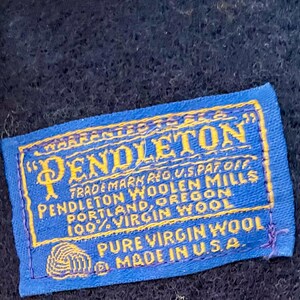 May include: A blue and yellow Pendleton label with the text "PENDLETON" and "TRADEMARK REG. U.S. PAT. OFF." The label also states "100% VIRGIN WOOL" and "MADE IN U.S.A."