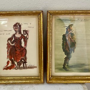 May include: A white ceramic mug with a black handle and the text "But First, Coffee" in a black, handwritten-style font. The mug is on a white surface.