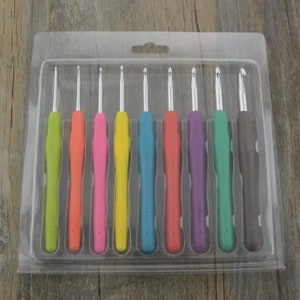 May include: A set of 8 colorful crochet hooks in a clear plastic case. The hooks are arranged in order of size, with the smallest hook on the left and the largest hook on the right. The hooks are made of metal with a plastic handle.