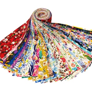 Pode incluir: Um rolo de tiras de tecido floral em várias cores. Os tecidos apresentam uma variedade de padrões florais em vermelho, azul, amarelo e rosa. As tiras são abertas, mostrando os vários desenhos.