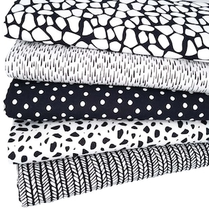 May include: Five different black and white fabric swatches with various patterns. The patterns include a pebble pattern, a thin line pattern, a polka dot pattern, a larger spot pattern, and a woven pattern.