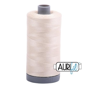 May include: A spool of pale beige thread, featuring a grey top and base. The thread is neatly wound, with the Aurifil logo visible. Suitable for sewing and quilting. The thread is perfect for various craft projects.
