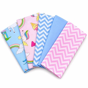 Peut inclure: Un ensemble de cinq carrés de tissu pliés présentant divers motifs, dont un drap bleu clair avec des châteaux et des arcs-en-ciel, un drap rose avec des licornes et des cornets de glace, un imprimé chevron bleu, un bleu clair uni et un chevron rose.