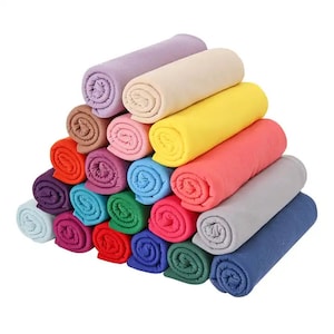 Può includere: Un mucchio di 18 coperte in pile arrotolate in vari colori, tra cui viola, rosa, giallo, rosso, blu e verde.
