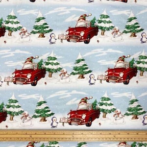 May include: A repeating pattern on light blue fabric features red vintage cars driven by gnomes wearing Santa hats. Snowmen, penguins, and Christmas trees are also present, creating a festive holiday scene.