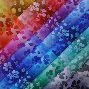Peut inclure: Une collection d'échantillons de tissu dans un spectre de couleurs, des oranges et rouges chauds aux bleus et verts froids. Chaque échantillon présente un motif floral avec des fleurs et des feuilles blanches. Le tissu est disposé en diagonale, mettant en valeur la variété des teintes et des motifs.