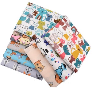 Könnte beinhalten: Ein Stapel bunter Stoffstücke mit verschiedenen Tiermustern. Designs umfassen Katzen, Hunde und abstrakte Muster in Blau-, Grün-, Rosa- und Grautönen. Die Stoffe sind gefaltet und gestapelt, was die Vielfalt der Muster zeigt.