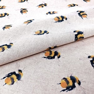 May include: A beige fabric with a repeating pattern of yellow and black bumblebees. The fabric is folded in half, showing the pattern on both sides.