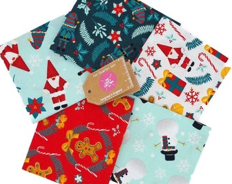 Könnte beinhalten: Ein Set aus sechs Stoffquadraten im Format "Fat Quarter" mit Weihnachtsmotiven. Die Stoffe zeigen verschiedene festliche Designs, darunter Weihnachtsmann, Schneemänner, Lebkuchenmänner, Zuckerstangen und Schneeflocken. Die Stoffe sind in verschiedenen Farben gehalten, darunter Rot, Grün, Blau und Weiß. Die Stoffe sind mit "Fat Quarter Set" und "The Crafty Cotton Co." beschriftet.