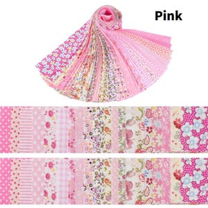 Puede incluir: Una colección de tiras de tela rosa, enrolladas y desplegadas, con varios diseños florales y estampados. La palabra "Pink" se muestra. Ideal para acolchar y manualidades. La tela es adecuada para diversos proyectos.