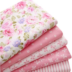 May include: A stack of five pink fabric squares with different patterns. The top square has a floral print, the second has small white dots, the third has white bows, the fourth has pink bows, and the bottom square has white stripes.