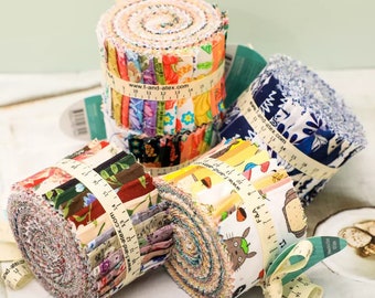 May include: Four rolls of colorful fabric scraps, each with a different pattern. The fabric rolls are wrapped with a measuring tape and have a website address printed on them. The fabric rolls are on a white surface.