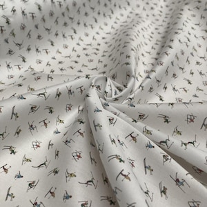 May include: White fabric with a repeating pattern of skiers in colourful clothing on white skis. The fabric is folded and has a slight sheen.