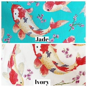 Könnte beinhalten: Zwei Stoffmuster mit einem Muster aus roten, weißen und goldenen Koi-Karpfen und rosa Blüten. Das obere Muster ist in einem leuchtenden Türkis gehalten und mit "Jade" beschriftet. Das untere Muster ist cremeweiß und mit "Elfenbein" beschriftet.