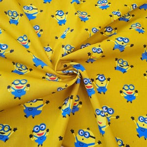 Puede incluir: Tela amarilla con un patrón repetido de Minions de dibujos animados que llevan un mono azul y gafas de protección. Los Minions sonríen y tienen los brazos levantados en el aire.