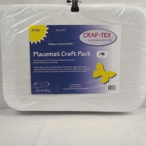May include: A Placemat Craft Pack wrapped in clear plastic. The label reads "Craf-Tex Double-Sided Fusible". A yellow butterfly graphic is on the label. The pack includes four 13" x 18" pieces of fabric.