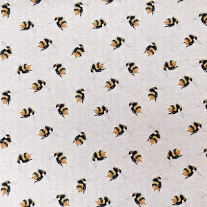 May include: A white fabric with a repeating pattern of yellow and black bumblebees. The bees are scattered randomly across the fabric.