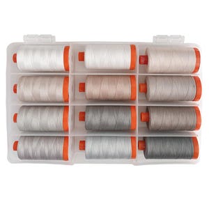 May include: A clear plastic storage box with 12 spools of thread. The spools are arranged in three rows of four. The spools are white, beige, and gray.