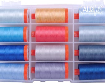 Op de afbeelding: Een doorzichtige plastic organizer gevuld met twaalf spoelen kleurrijk garen. De garenkleuren zijn lichtblauw, oranje, blauw, rood, zilver en marineblauw. Elke spoel heeft oranje uiteinden en is voorzien van het merk "Aurifil".
