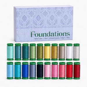 May include: A set of 20 small spools of 100% cotton thread in various colors, arranged in two rows. The packaging box is light blue with a decorative pattern and the text Foundations, 100% Cotton, 40wt, 20 Small Spools, 164yd, 150m.