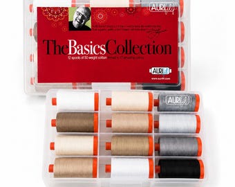 Könnte beinhalten: Ein durchsichtiger Kunststoff-Aufbewahrungskoffer mit 12 Spulen aus 50er Baumwollgarn in neutralen Farben. Das rote Etikett trägt die Aufschrift The Basics Collection und das Aurifil-Logo. Jede Spule hat orangefarbene Enden.